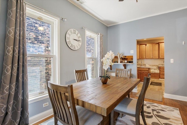 dining area with ornamental molding and light hardwood / wood-style flooring