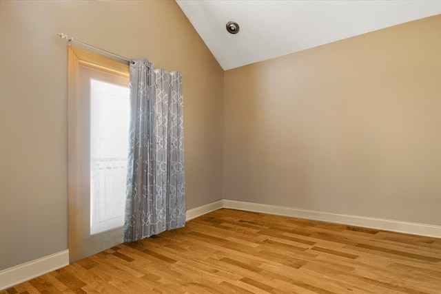 spare room featuring light hardwood / wood-style floors and vaulted ceiling