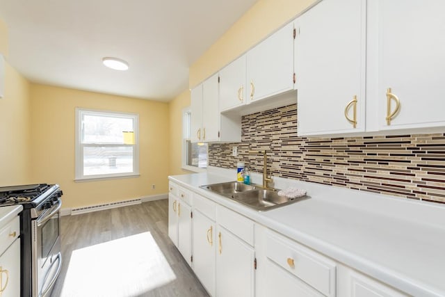 kitchen with sink, light hardwood / wood-style flooring, stainless steel range with gas stovetop, white cabinets, and decorative backsplash