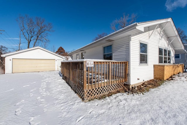 view of snow covered exterior with an outbuilding, a garage, and a deck