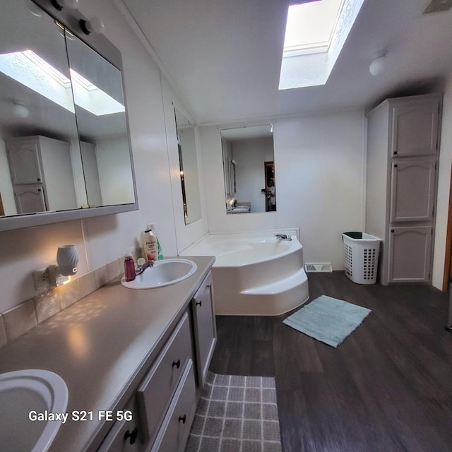 bathroom with a bathing tub, vanity, lofted ceiling with skylight, and hardwood / wood-style flooring