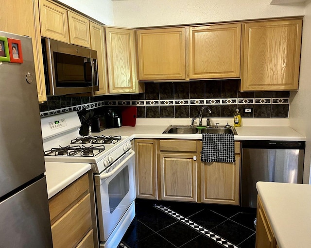 kitchen featuring dark tile patterned floors, decorative backsplash, appliances with stainless steel finishes, and sink