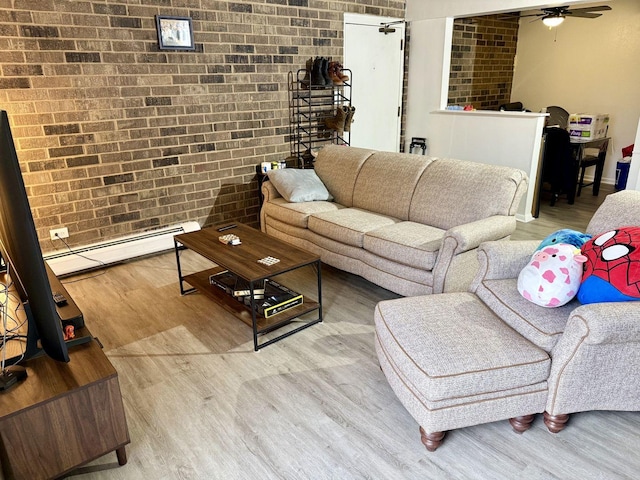 living room with ceiling fan, a baseboard radiator, brick wall, and hardwood / wood-style floors