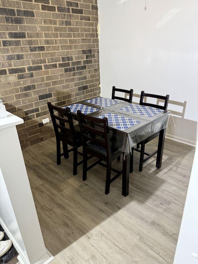 dining space with brick wall and hardwood / wood-style floors