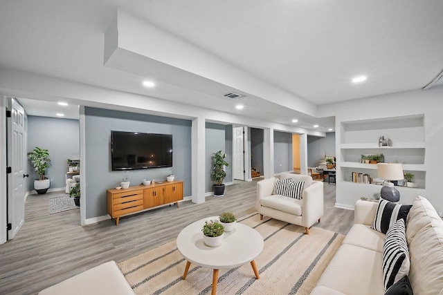 living room with built in features and light wood-type flooring