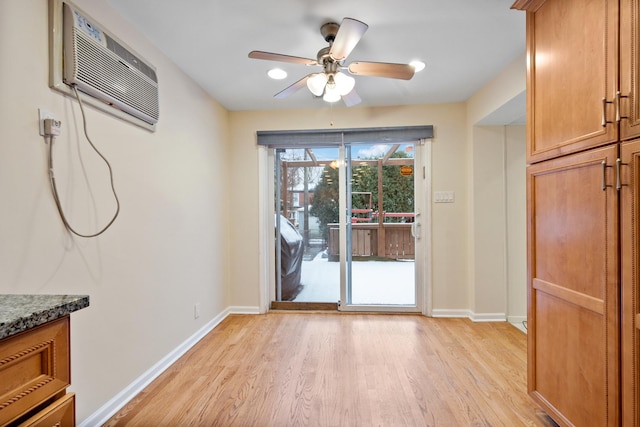 doorway featuring a wall unit AC, light wood-style flooring, and baseboards