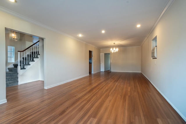 empty room with baseboards, stairway, ornamental molding, wood finished floors, and a notable chandelier