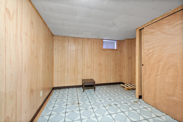 basement featuring baseboards, light floors, and wooden walls