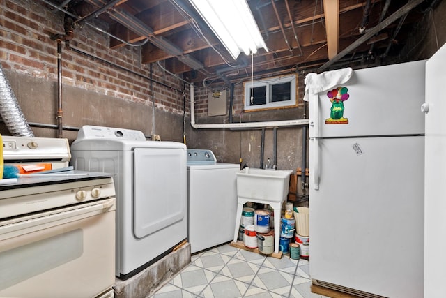 clothes washing area featuring light floors, washing machine and dryer, a sink, brick wall, and laundry area