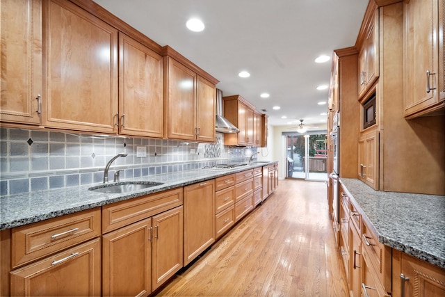 kitchen with tasteful backsplash, light wood-style floors, a sink, ceiling fan, and gas cooktop