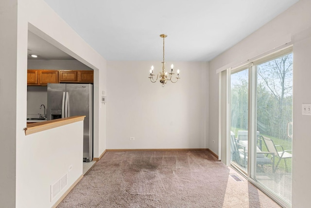 unfurnished dining area featuring carpet floors, an inviting chandelier, and sink