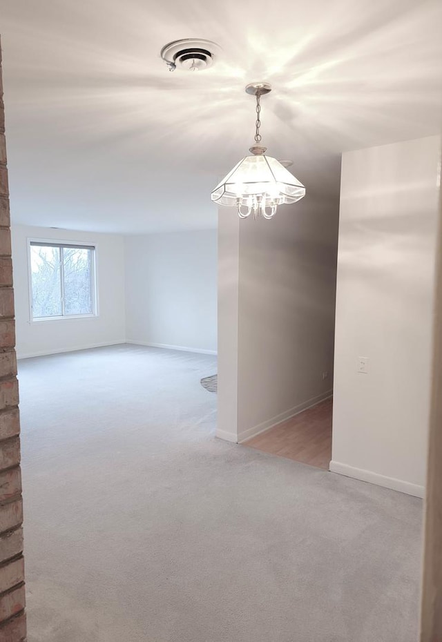 empty room featuring a chandelier and light carpet