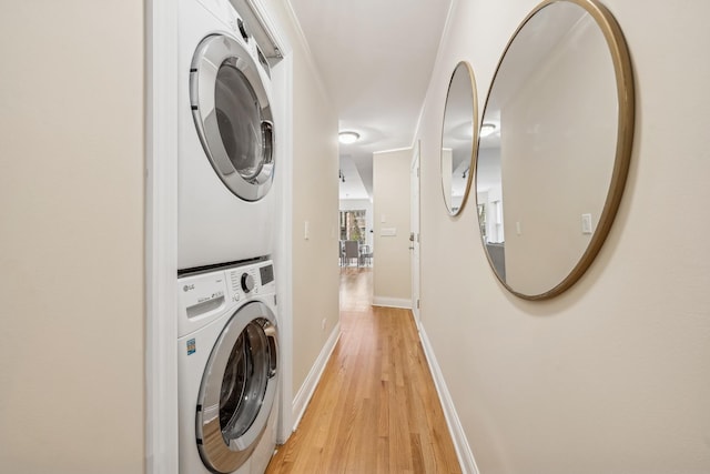 laundry area with light hardwood / wood-style flooring and stacked washer and clothes dryer