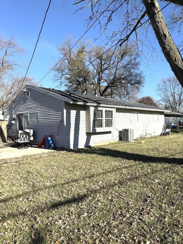 view of side of property with a patio area, central air condition unit, and a lawn