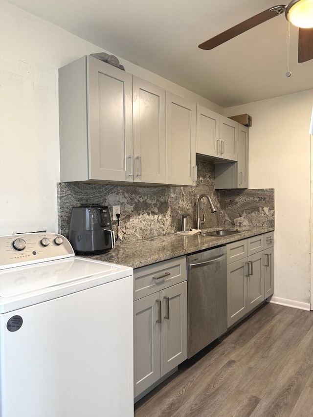 kitchen with tasteful backsplash, gray cabinetry, dishwasher, dark wood-style floors, and washer / clothes dryer