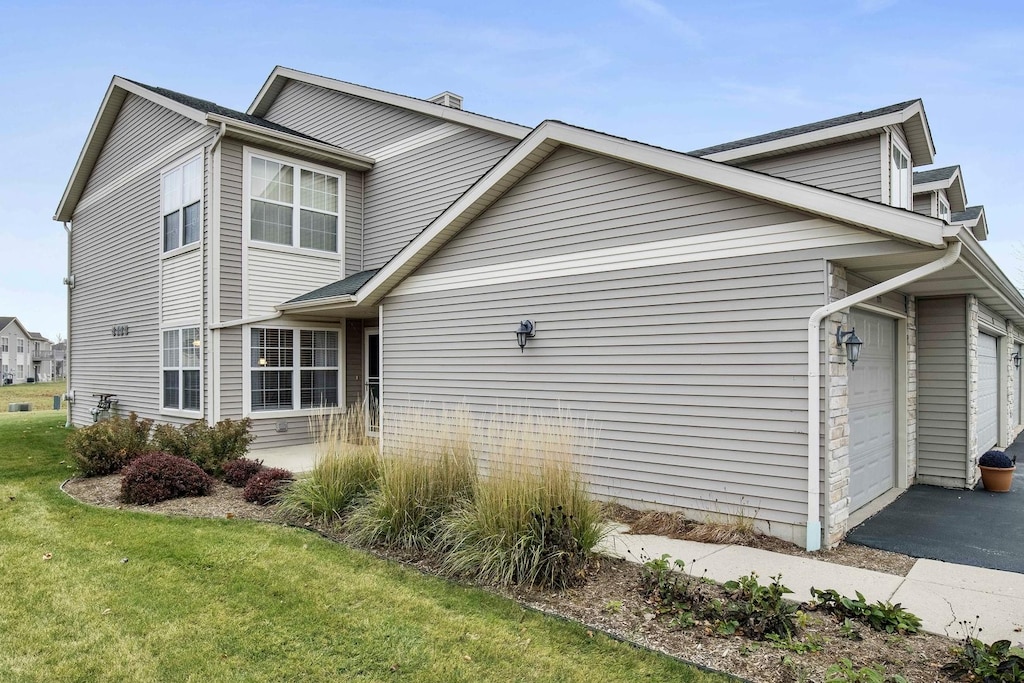 view of property exterior featuring a garage and a lawn