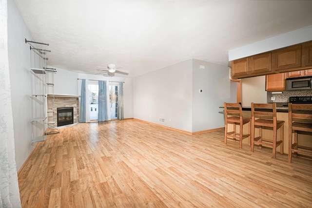 living room featuring a tile fireplace, light wood-type flooring, and ceiling fan