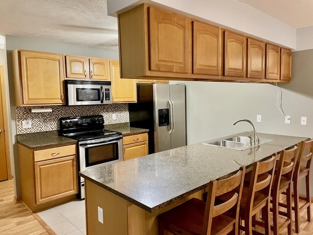 kitchen with a breakfast bar, sink, kitchen peninsula, and stainless steel appliances