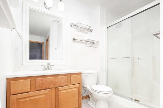 bathroom featuring vanity, toilet, and a shower with shower door