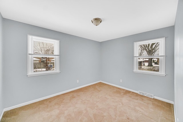 empty room with light colored carpet and a healthy amount of sunlight