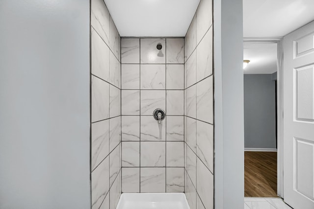 bathroom with tiled shower and hardwood / wood-style flooring