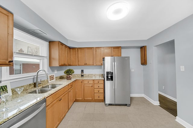 kitchen featuring sink, light stone countertops, and stainless steel appliances