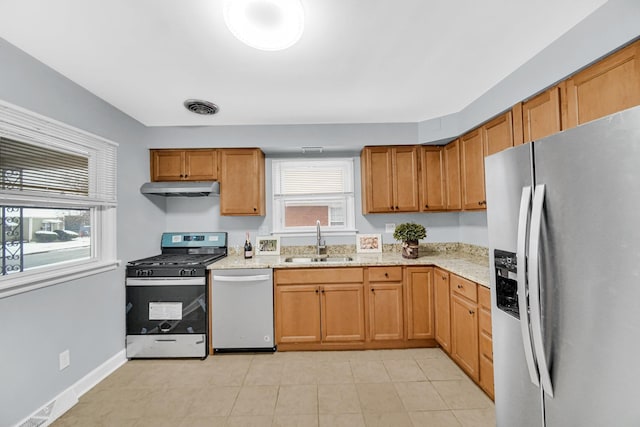 kitchen with light stone counters, sink, light tile patterned floors, and stainless steel appliances