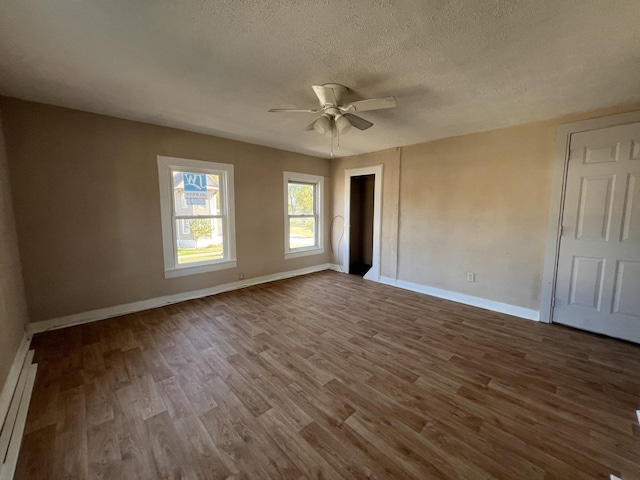 spare room with hardwood / wood-style floors, a textured ceiling, a baseboard radiator, and ceiling fan