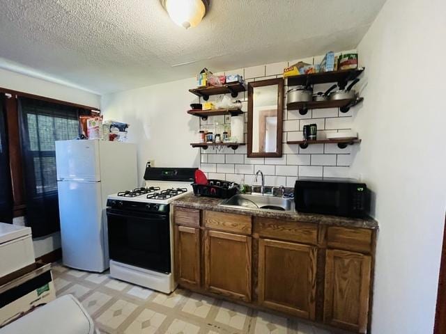 kitchen featuring backsplash, sink, a textured ceiling, and white appliances