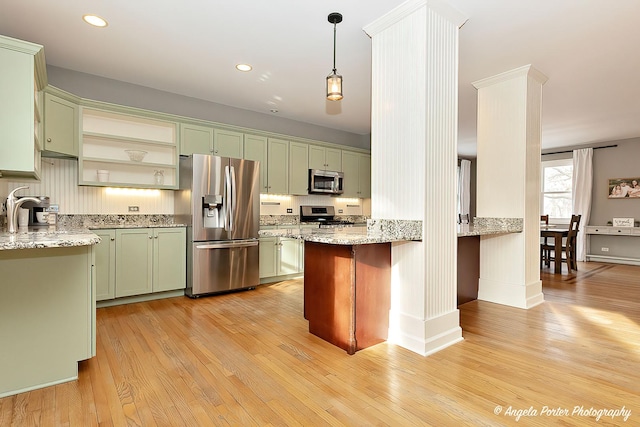 kitchen featuring decorative light fixtures, light wood-type flooring, green cabinets, and appliances with stainless steel finishes