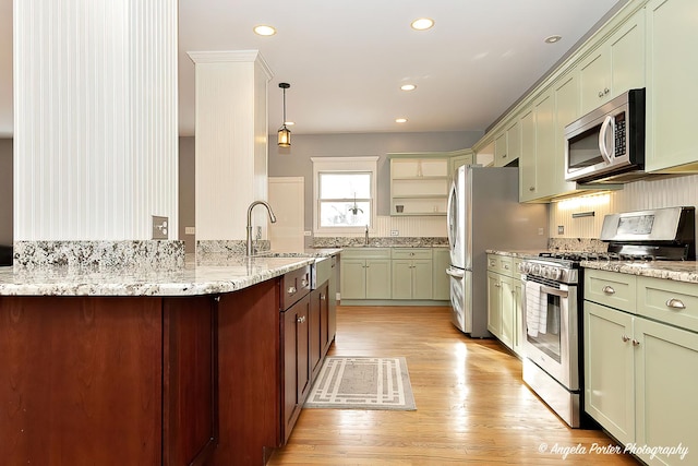 kitchen with sink, light stone counters, decorative light fixtures, and appliances with stainless steel finishes