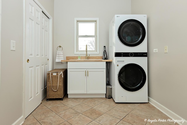 washroom featuring cabinets, light tile patterned floors, sink, and stacked washer and dryer