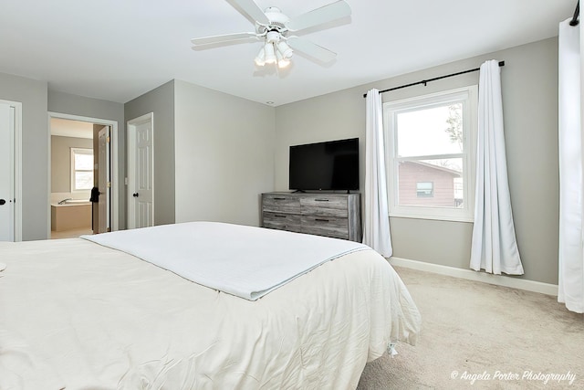 bedroom featuring light carpet, ensuite bath, and ceiling fan