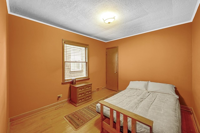 bedroom featuring crown molding, a textured ceiling, and light wood-type flooring