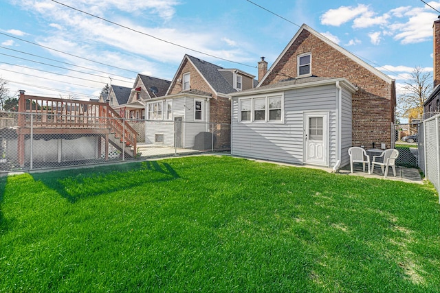 rear view of property featuring a yard and a wooden deck