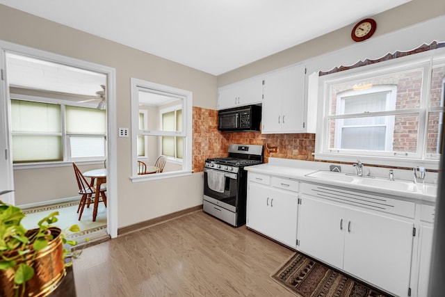 kitchen featuring gas range, sink, white cabinets, and light hardwood / wood-style floors