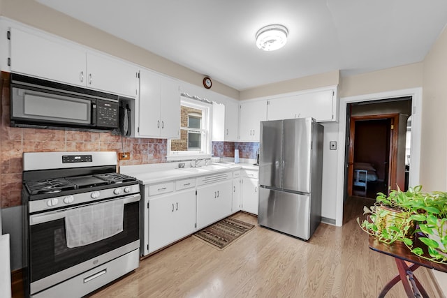 kitchen with light wood-type flooring, stainless steel appliances, white cabinetry, and backsplash