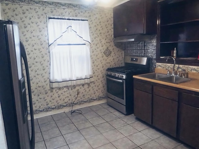 kitchen with ventilation hood, sink, light tile patterned floors, appliances with stainless steel finishes, and dark brown cabinets