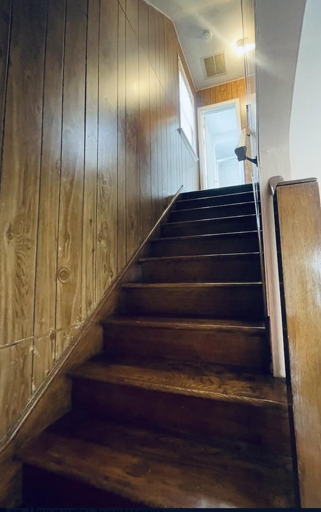 staircase featuring wood walls