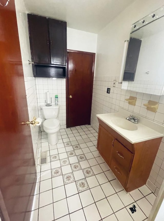 bathroom featuring tile patterned floors, vanity, toilet, and tile walls