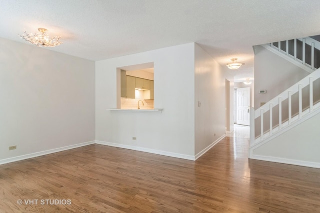 interior space with a textured ceiling, sink, dark hardwood / wood-style floors, and an inviting chandelier