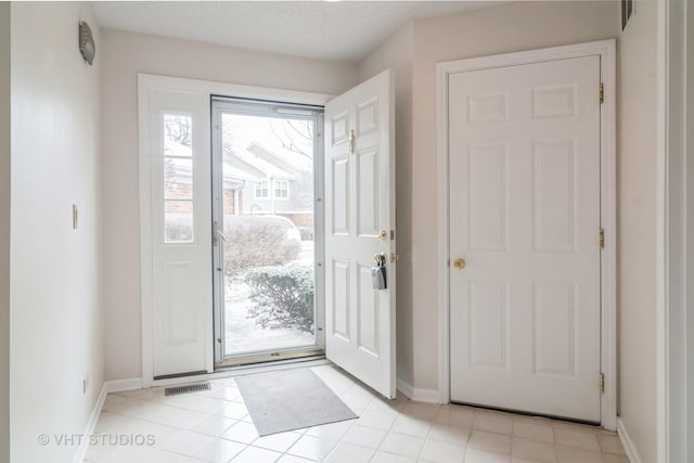 doorway to outside with light tile patterned floors and a textured ceiling