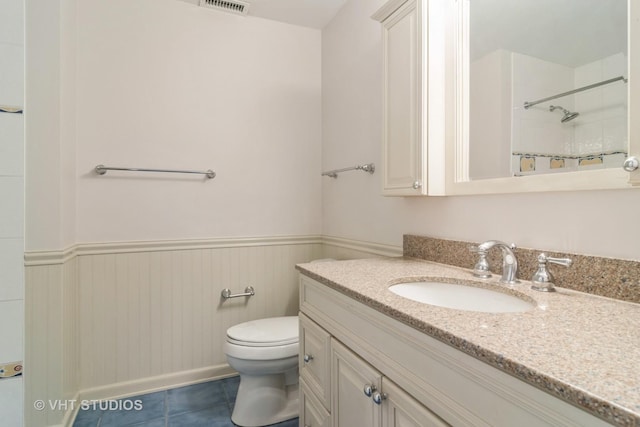 bathroom featuring tile patterned flooring, vanity, toilet, and tiled shower