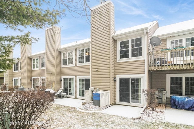 snow covered rear of property with central AC unit