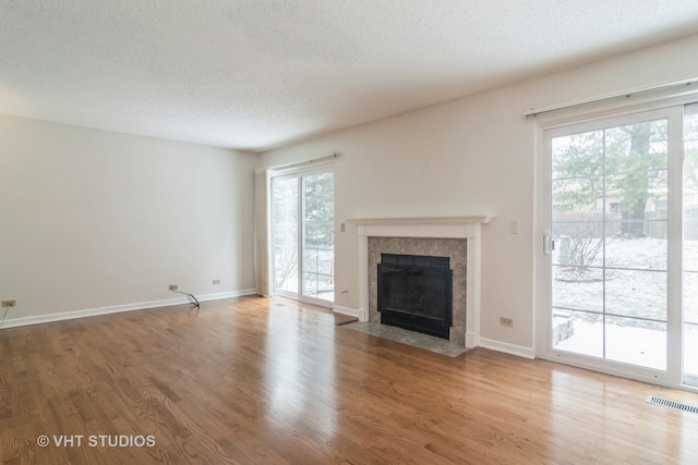 unfurnished living room featuring hardwood / wood-style flooring, a textured ceiling, and a tile fireplace