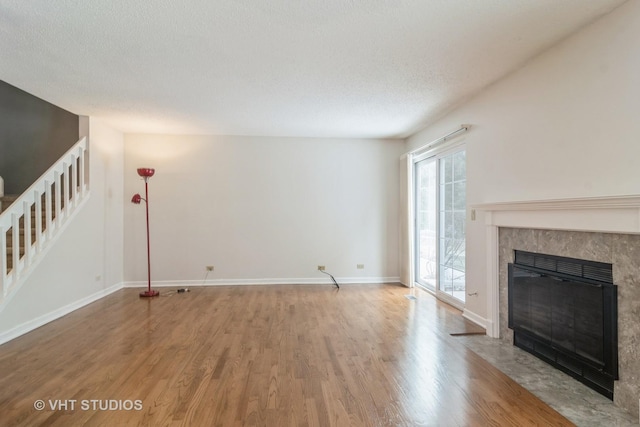 unfurnished living room with hardwood / wood-style flooring, a textured ceiling, and a tiled fireplace