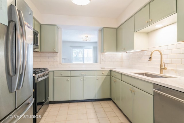 kitchen featuring sink, green cabinetry, appliances with stainless steel finishes, tasteful backsplash, and light tile patterned flooring