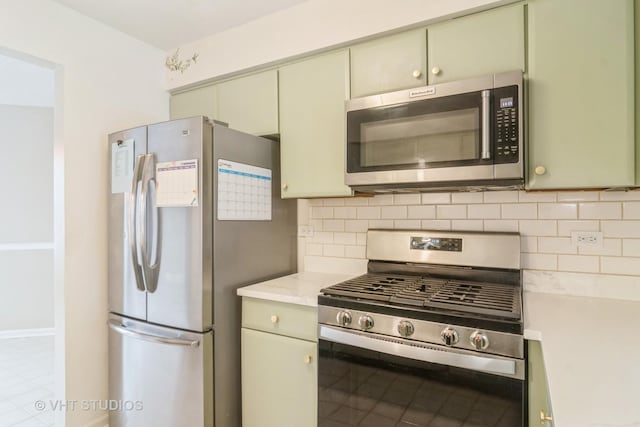 kitchen featuring light stone countertops, appliances with stainless steel finishes, backsplash, and green cabinetry