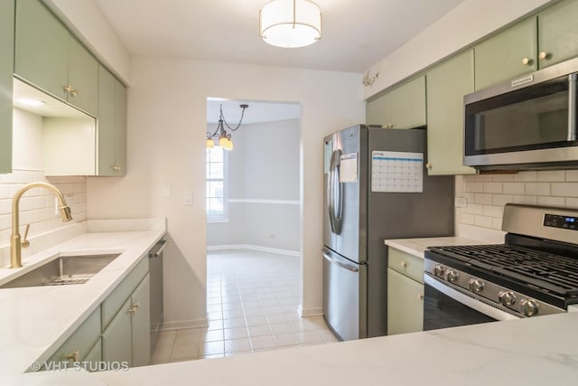 kitchen featuring backsplash, green cabinets, sink, and stainless steel appliances