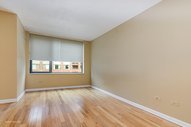 spare room with light hardwood / wood-style floors and a textured ceiling